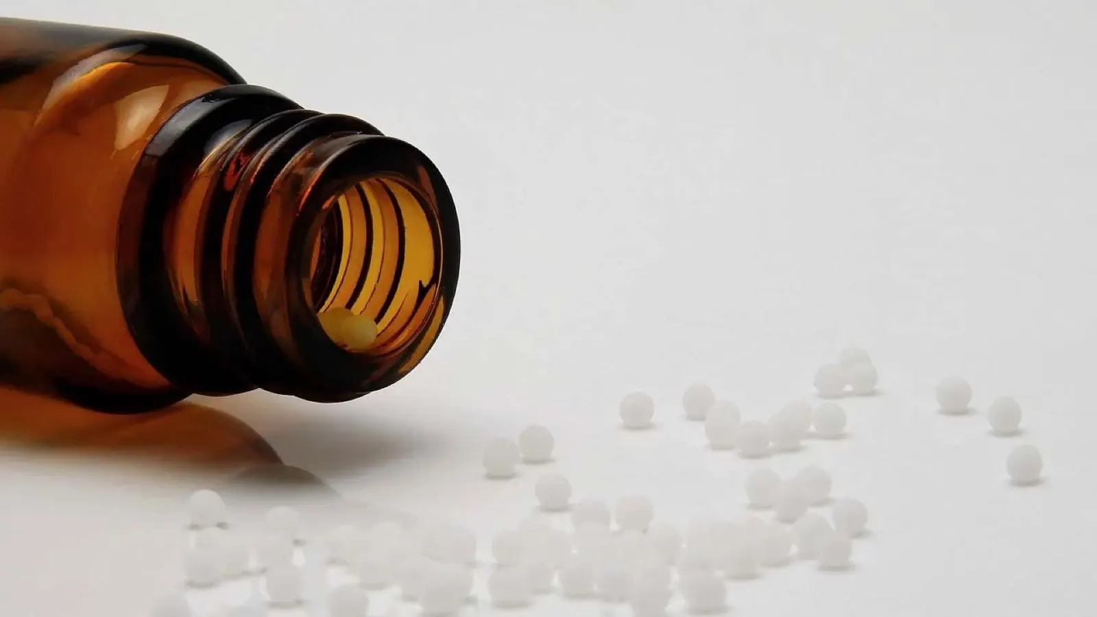 Braunglasflasche liegt auf der Seite, mit weißen Tabletten, die aus der Öffnung fallen.