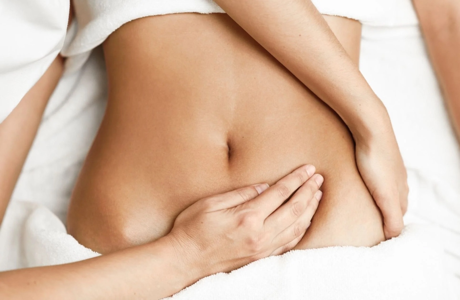 Close-up of a person's abdomen with hands placed on the side.