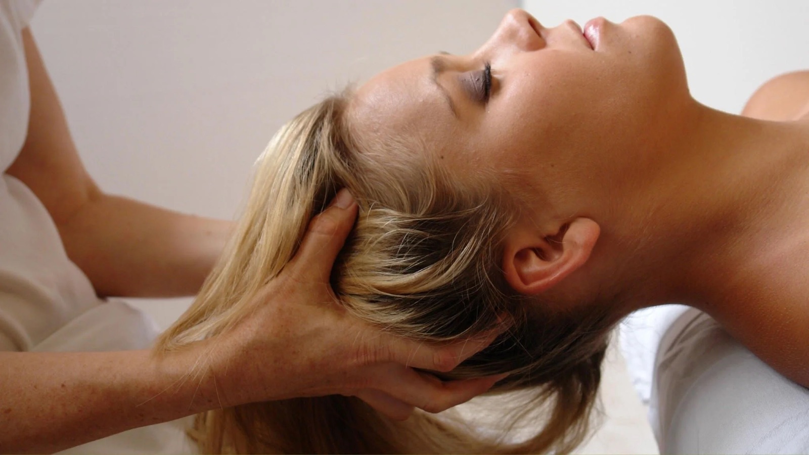 A woman receives a professional neck and head massage in a calm setting.