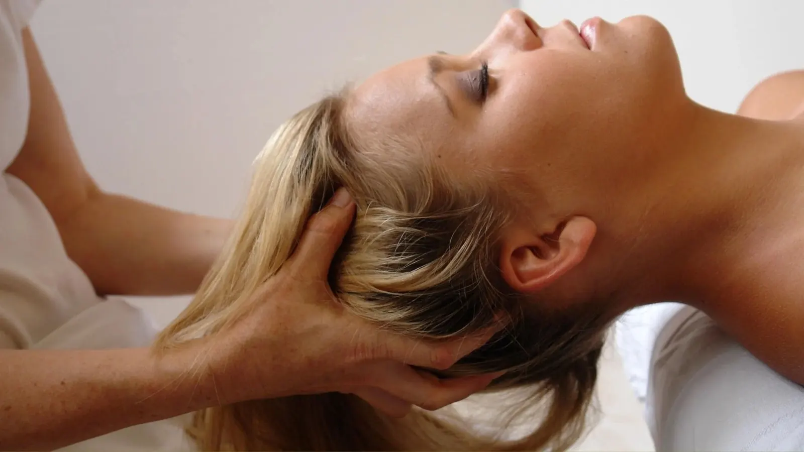 Eine Frau erhält eine professionelle Nacken- und Kopfmassage in einer ruhigen Umgebung.