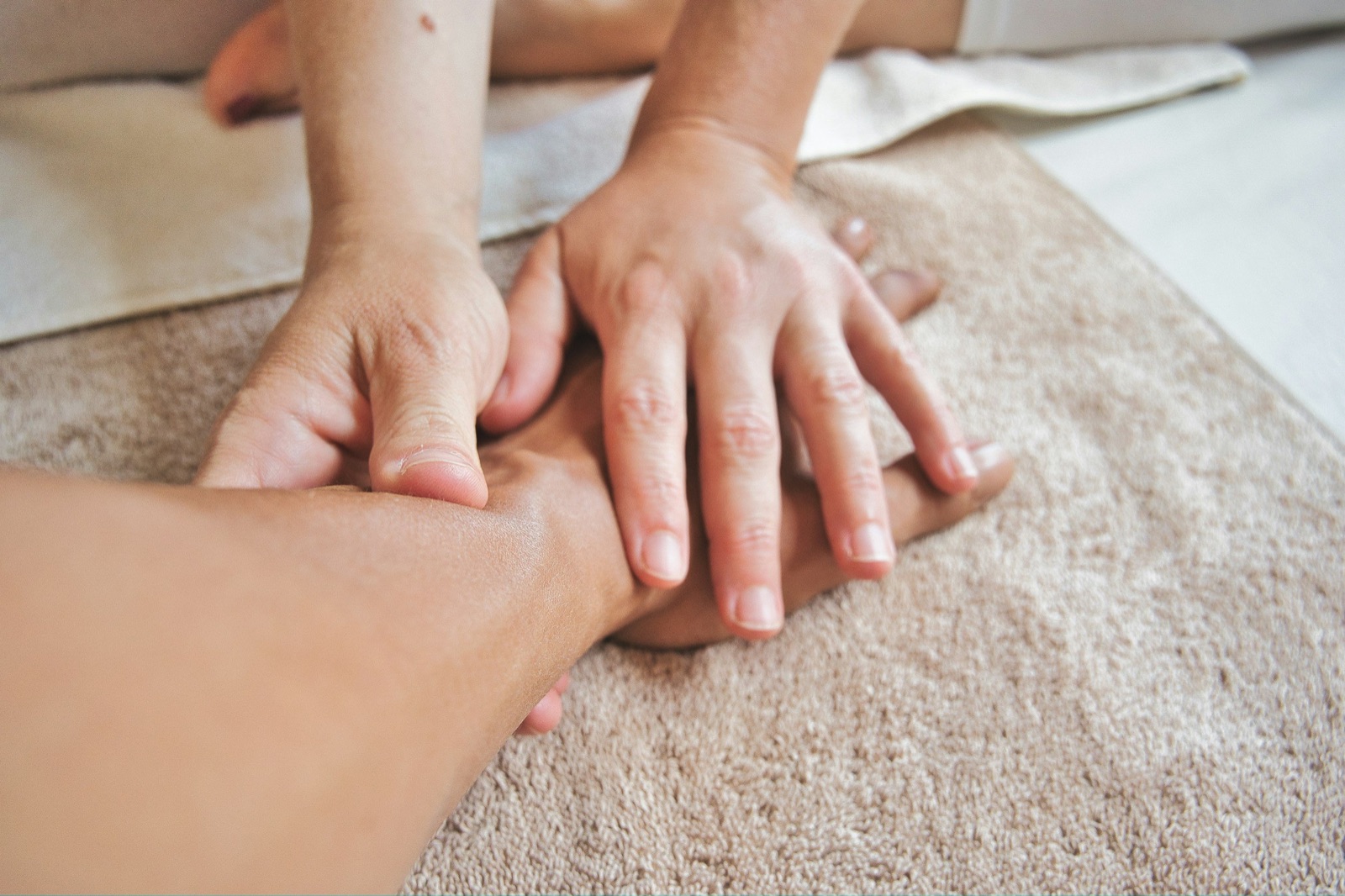 Person receiving a massage lying on a massage table, with several hands massaging.