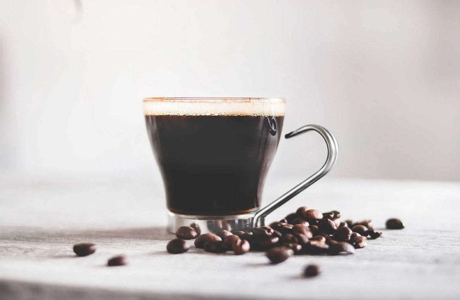 Cup of coffee with coffee beans in the foreground